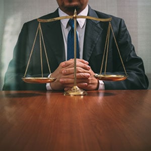 Corporate professional at desk, scales of justice symbolizing fairness in business litigation, office setting in the background.